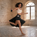 Black high-waisted flow skort with built-in shorts worn by a woman moving freely inside a sunlit stone heritage home in Deir El Qamar
