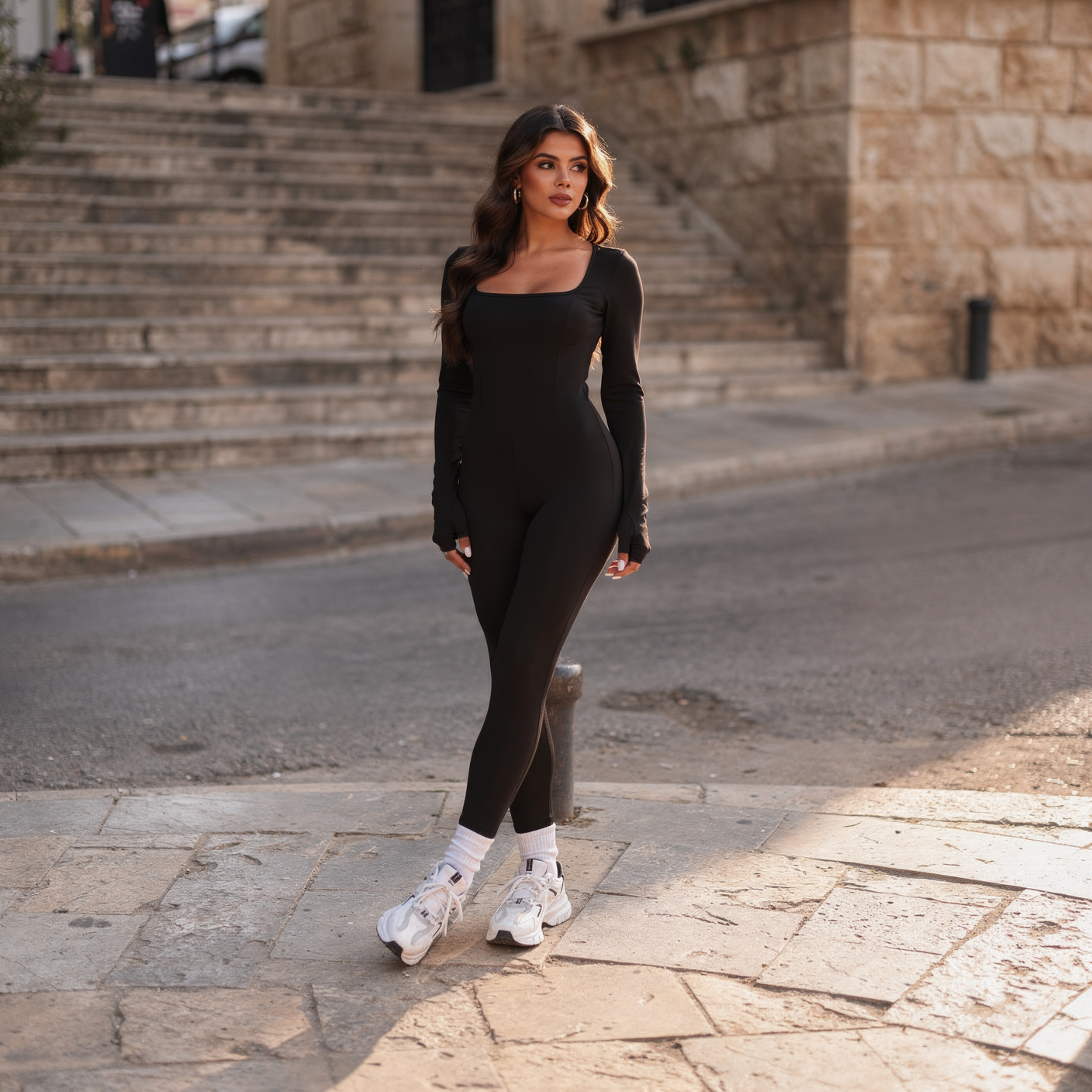 Sleek black long-sleeve performance suit for women, featuring a front zip and a sculpted, second-skin fit, photographed on an old street in Zahle.
