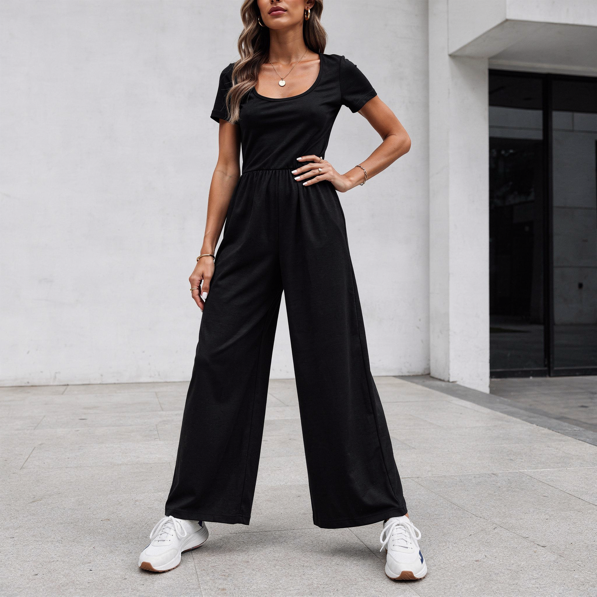 Tailored black wide-leg jumpsuit for women with a flattering V-neckline and defined waist, photographed in a clean studio setting.
